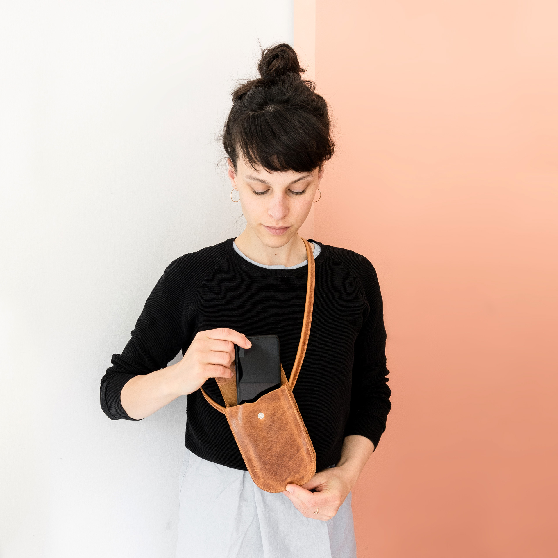 Model wears cell phone case IRA in cognac oiled and pulls out a cell phone