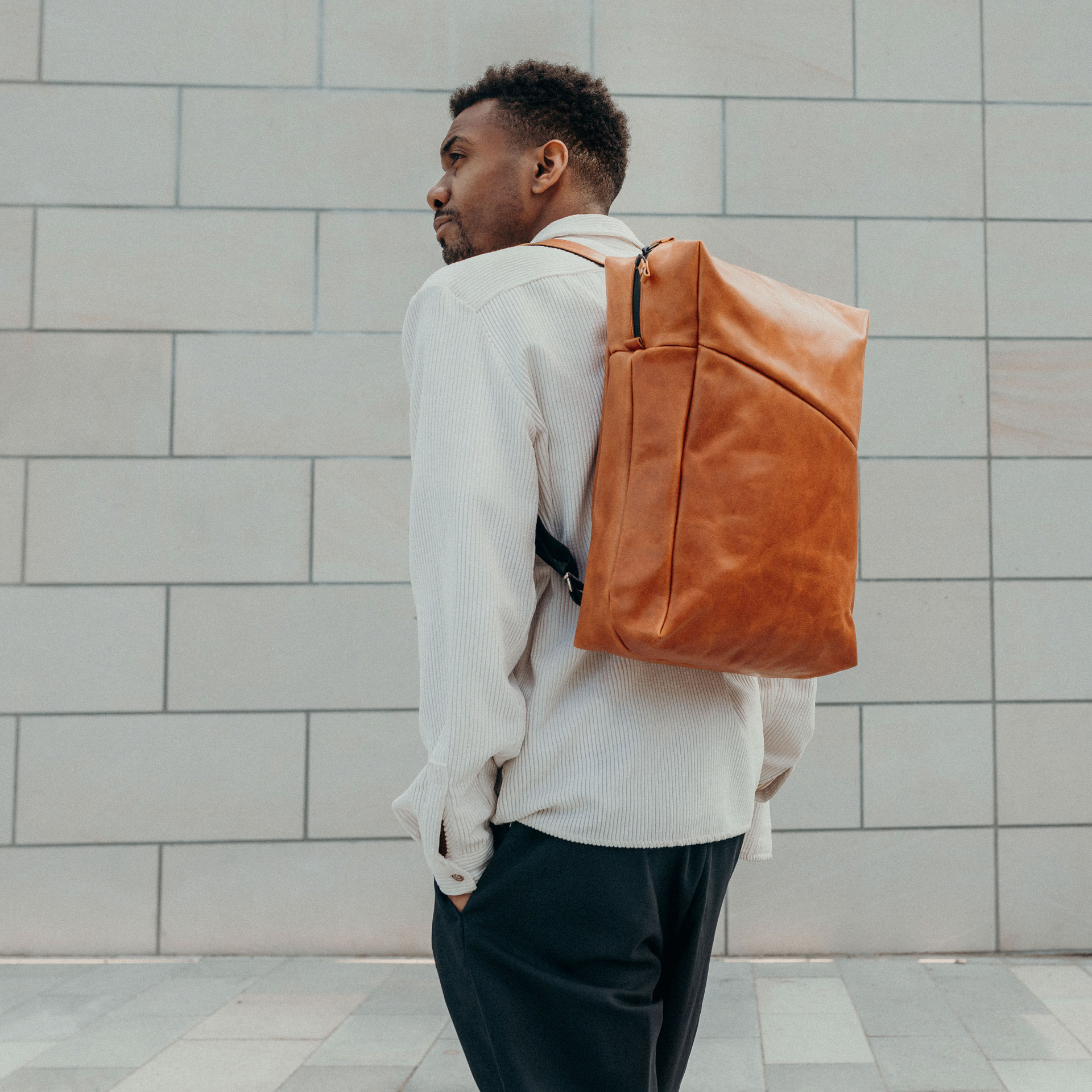 Male model wears backpack NEO Large in color cognac oiled on his back.