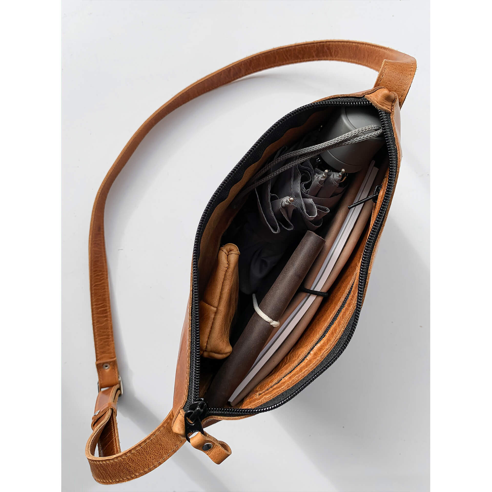 Interior view of shoulder bag IDA in cognac oiled filled with umbrella, notebook, wallet and utensil pocket