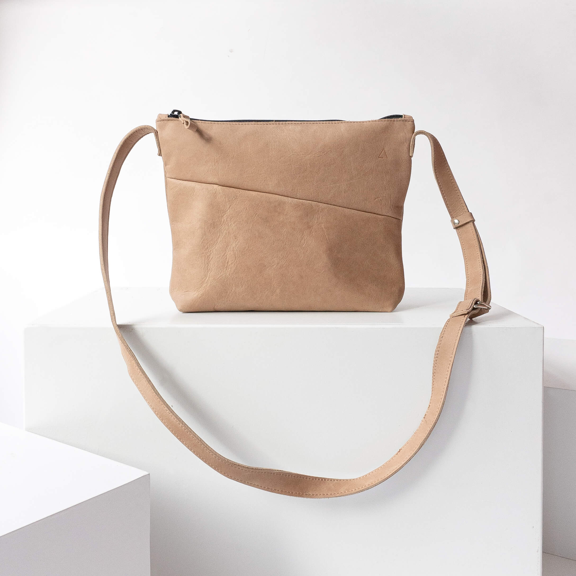 Shoulder bag IDA made of sustainable natural leather in light brown standing on block from the front