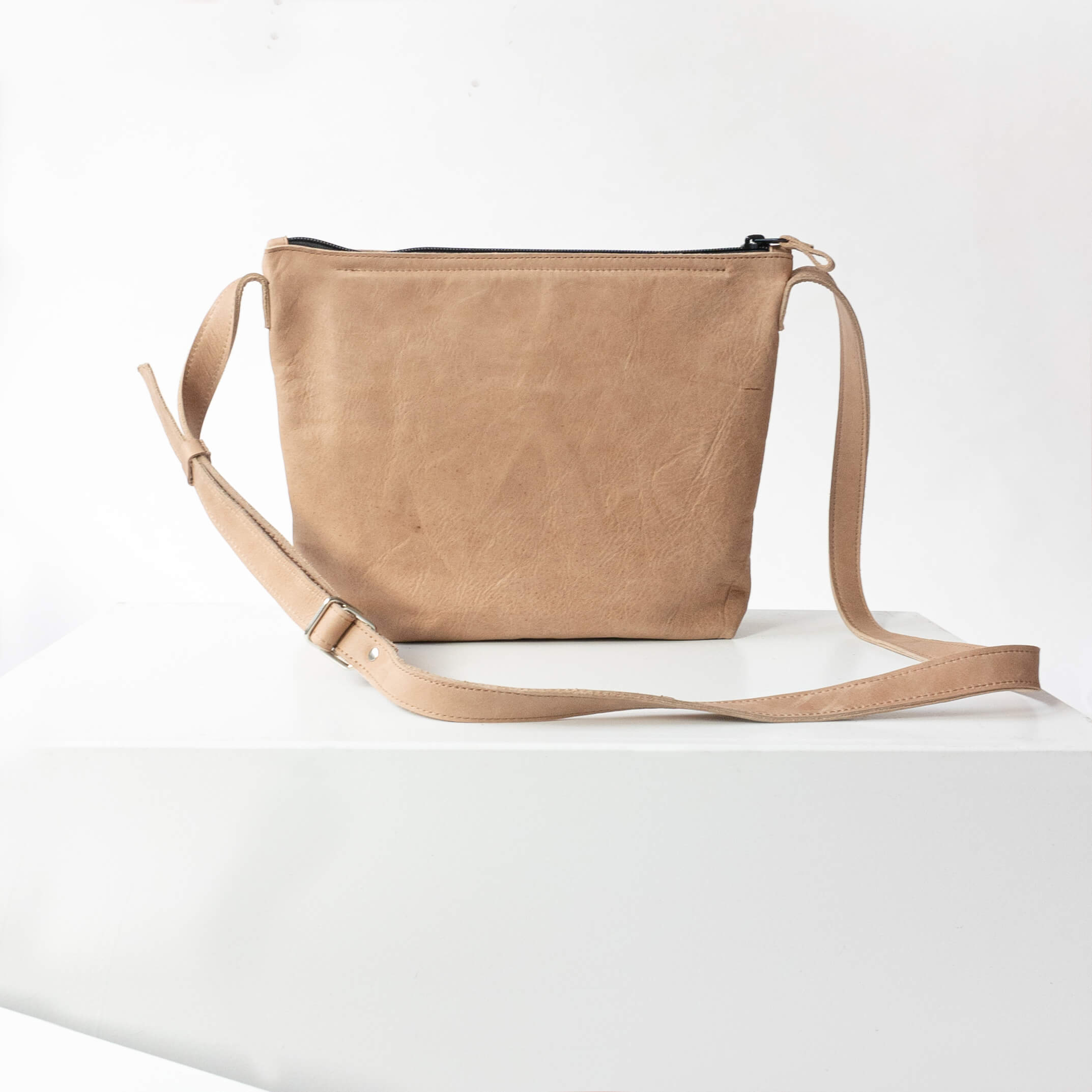 Back of the shoulder bag IDA made of sustainable natural leather in light brown standing on block