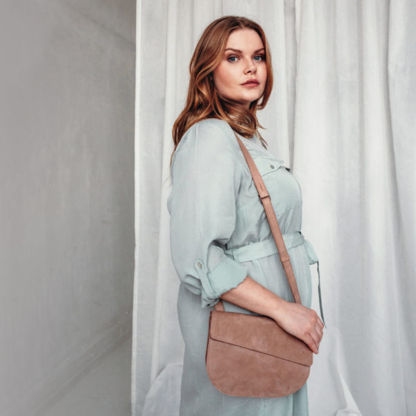 Model wears shoulder bag BEA in color light brown on one shoulder.