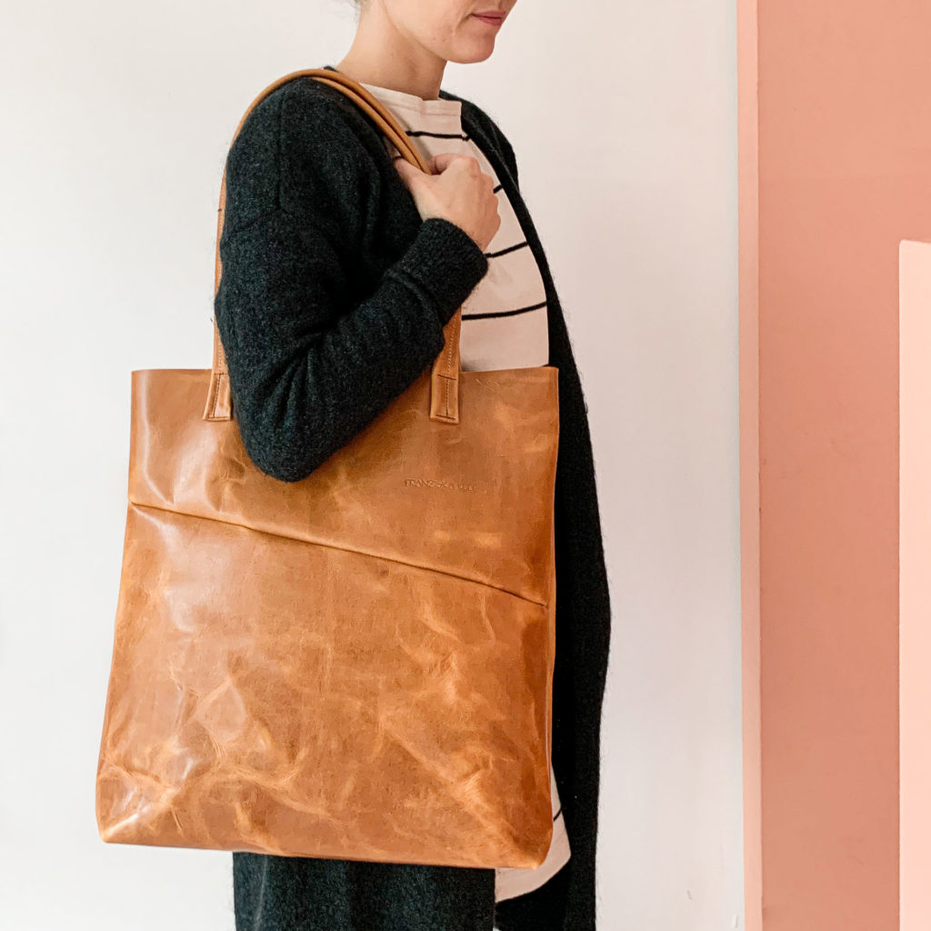 Model wears diaper bag MIA MIDI natural leather oiled cognac with long handles