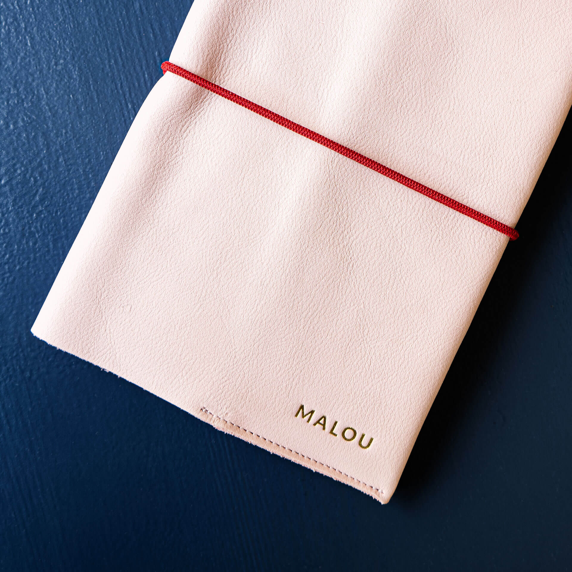 U-book cover EVE made of sustainable natural leather in pink with individual embossing in gold and red closure band