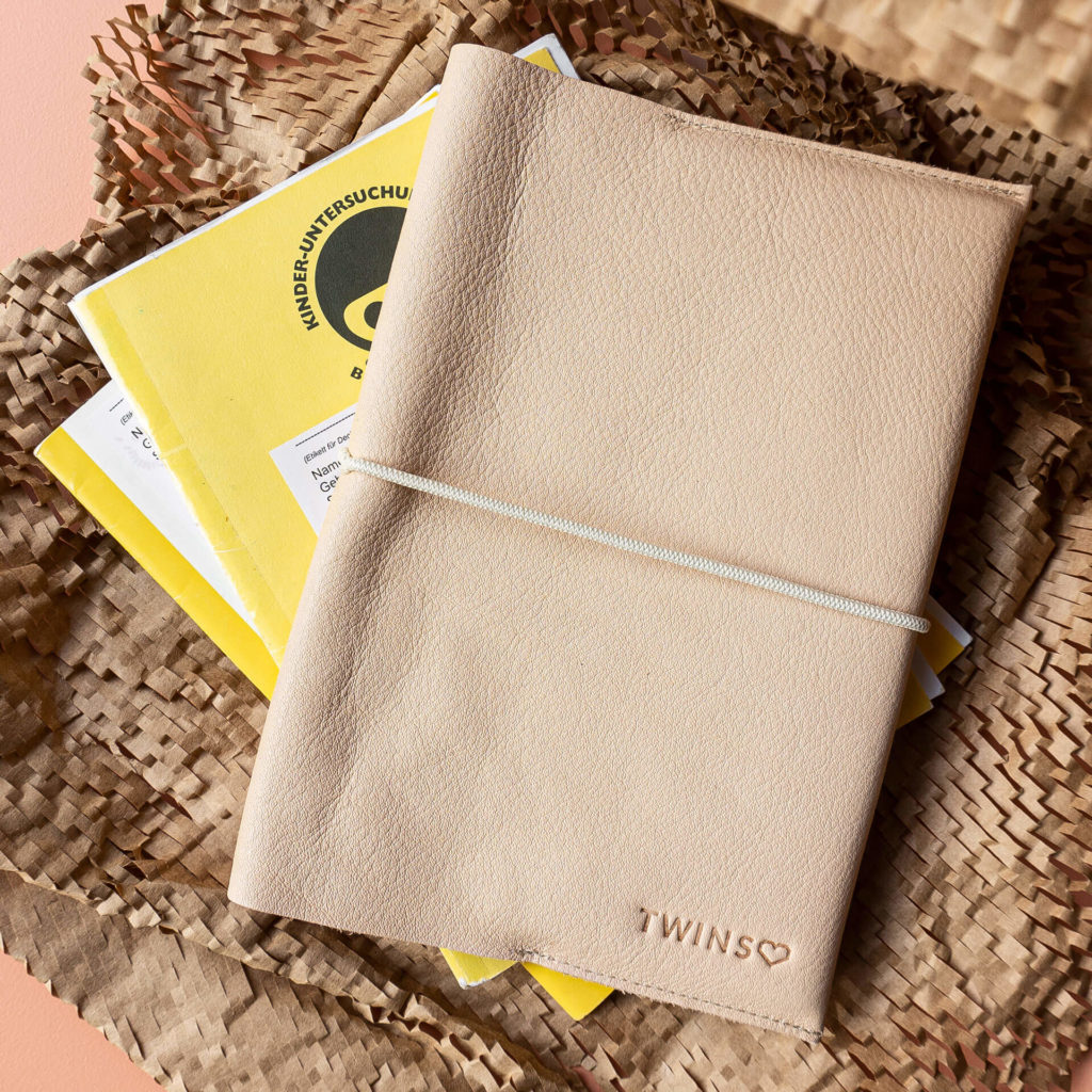 Mood Shot U-book cover EVE made of sustainable natural leather in beige, cream-colored ribbon and individual embossing in nature