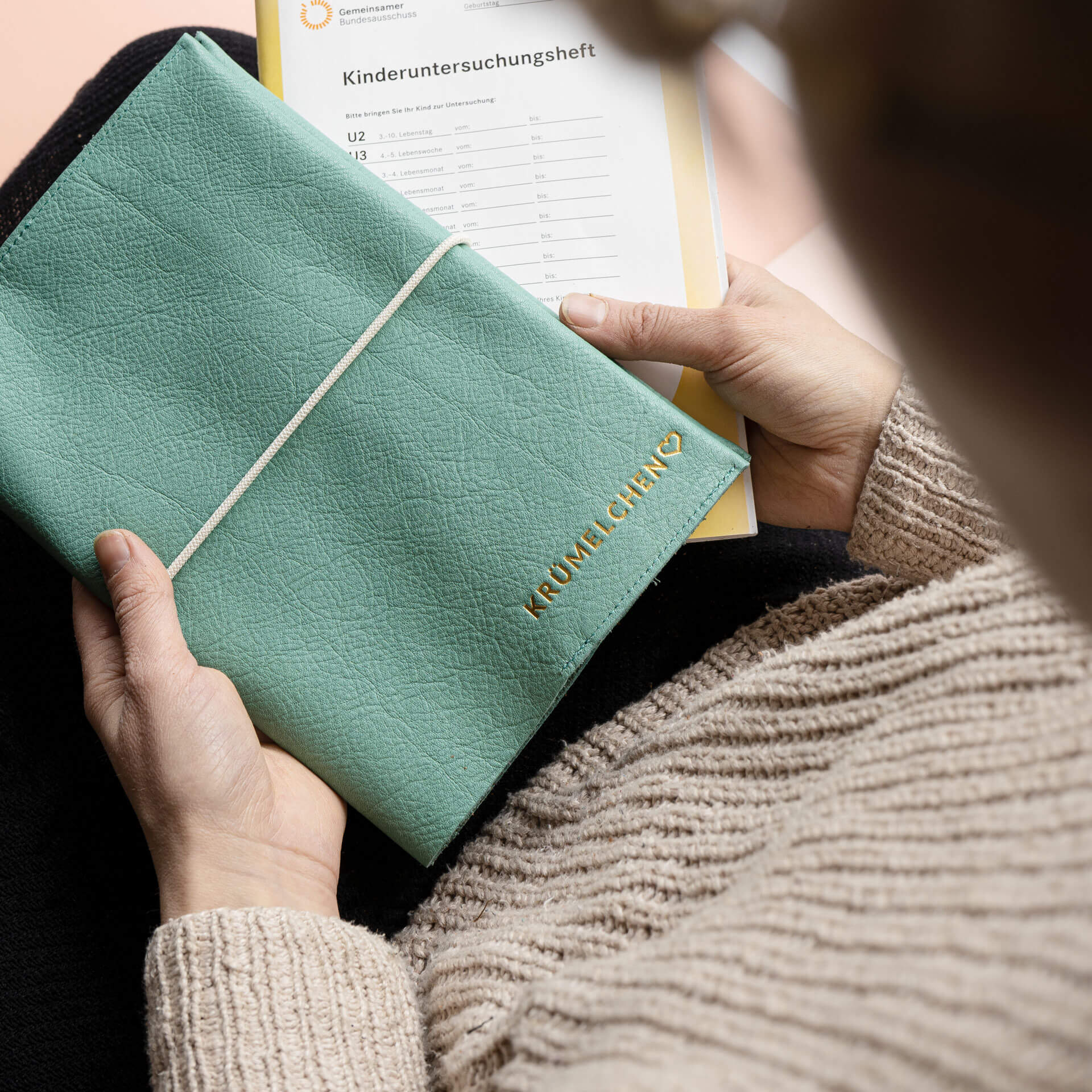 Woman holding U-booklet EVE in mint with individual embossing in gold and cream closure band together with U-booklet