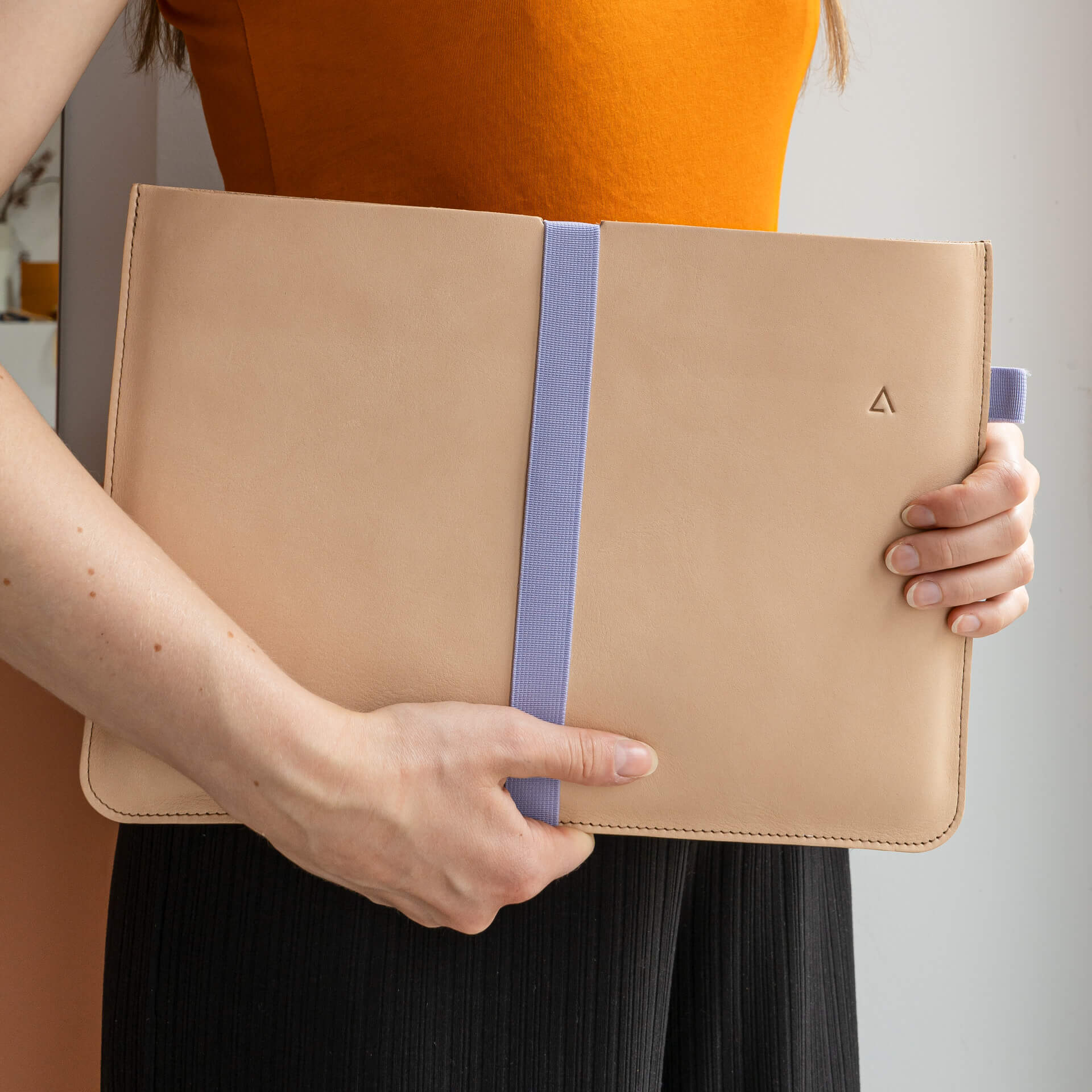 The FRANZISKA KLEE laptop sleeve in the color light brown - combined with a closure strap in the color lilac.